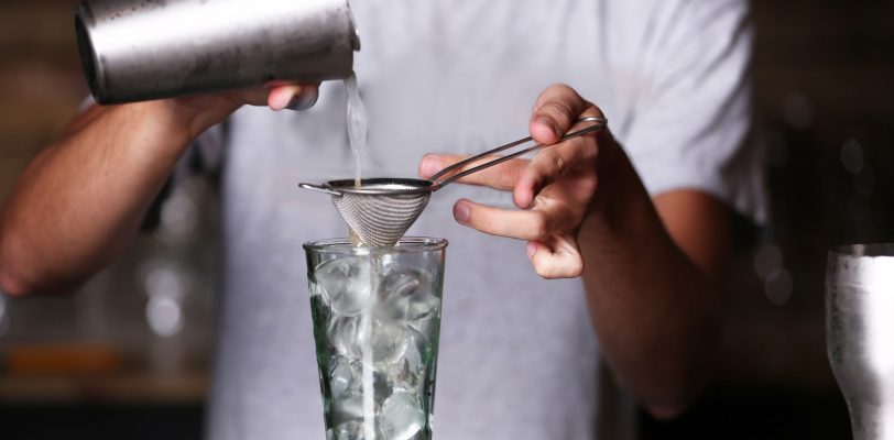 Barman mixing drinks with strainer