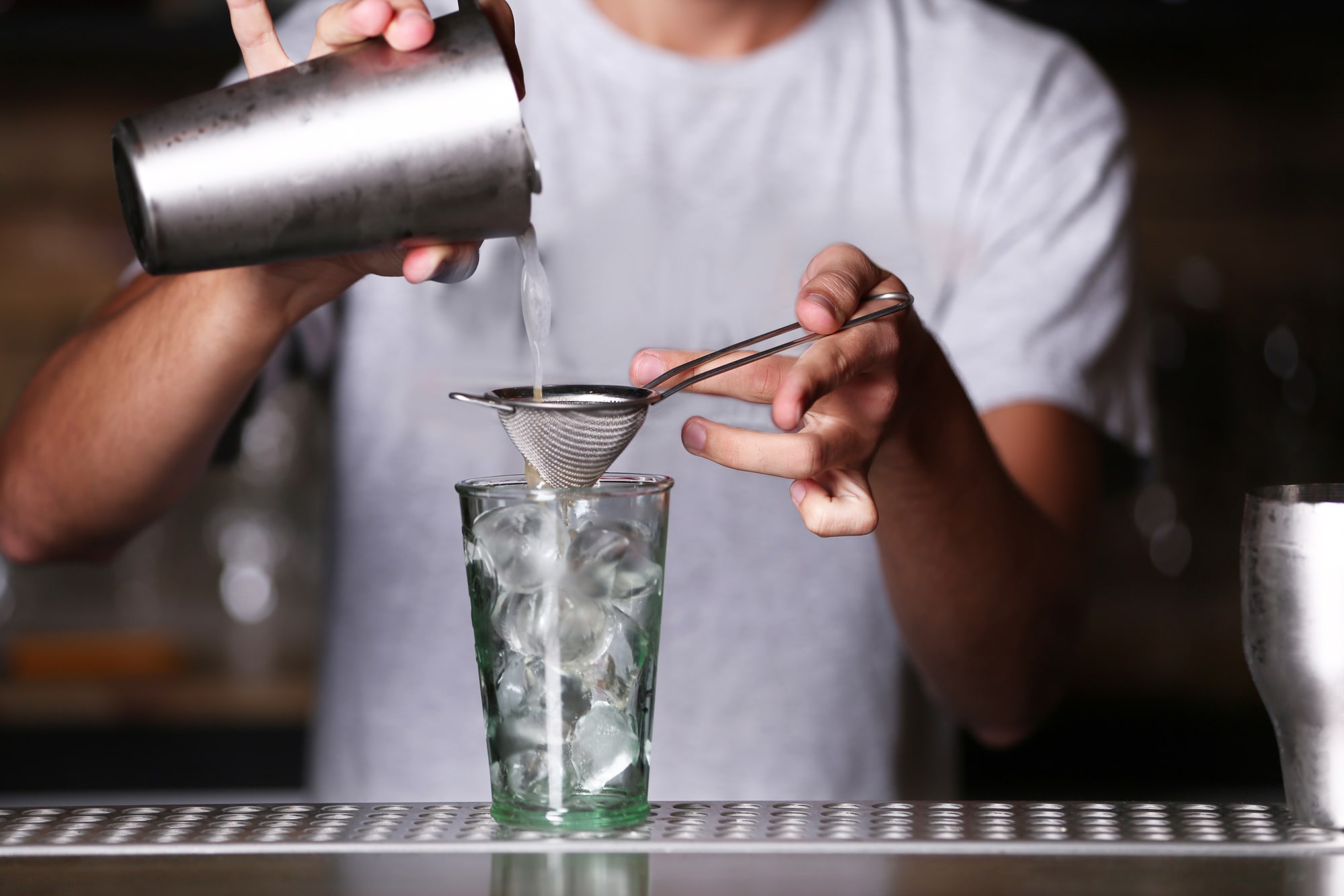 Barman mixing drinks with strainer