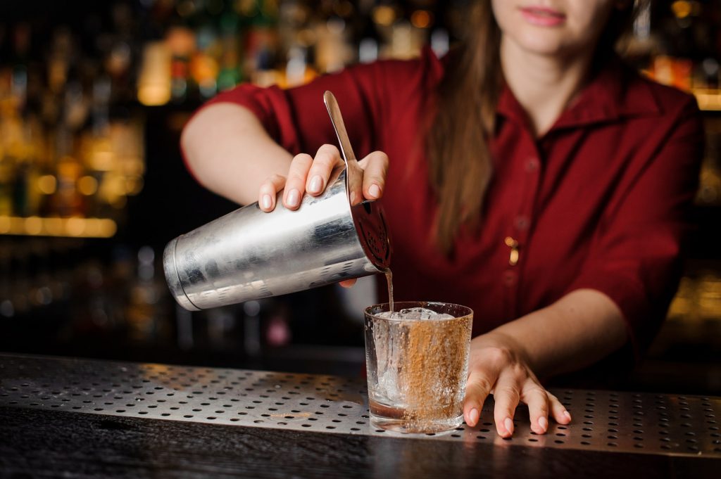 Bartender pouring liquid through a Hawthorne drink strainer